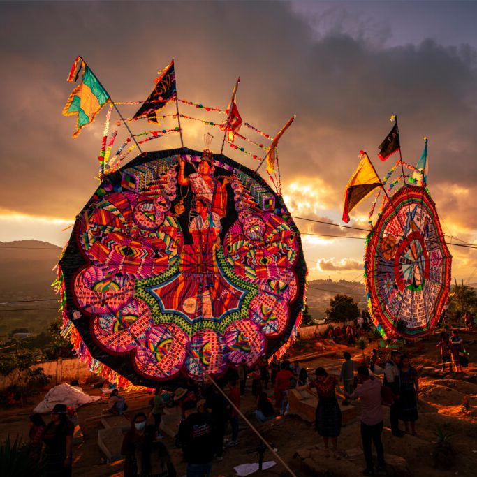 Dos grandes estructuras circulares decoradas con luces, al atardecer en un evento festivo.